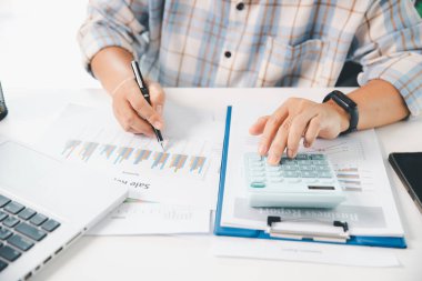 Ofisteki finans raporunu hesaplamak için hesap makinesi kullanan bir muhasebeci. işletme finansmanı, mali belgeleri düzenleyerek vergi hesaplama, gelir yatırımlarını takip etme, elle hesaplama.
