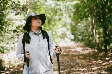 Sırt çantalı genç bir gezgin ulusal parkta ya da ormanda yürüyor. Doğada eğlence sporu. Kadın çantası, ormanda yürüyüş için el sallıyor. Ormanda macera. Sırt çantasıyla yürüyüş