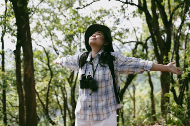 Sırt çantalı genç bir gezgin ulusal parkta ya da ormanda yürüyor. Doğada eğlence sporu. Kadın çantası, ormanda yürüyüş için el sallıyor. Ormanda macera. Sırt çantasıyla yürüyüş