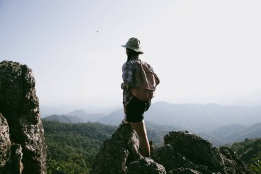 Dağın tepesinde kadın yürüyüşçü. Kolları dağın tepesinde gezen başarılı genç bir kadın zaferin tadını çıkarıyor. Gezgin dünyayı keşfediyor. Sırt çantalı yürüyüşçüler dinleniyor. Spor ve başarı konsepti.