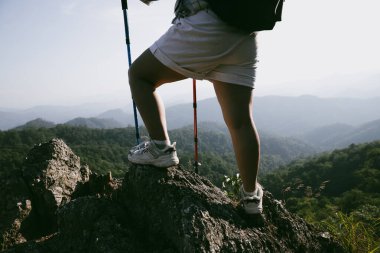Yürüyüş botu. Dağların tepesindeki yürüyüş yolunda botlu kadın bacaklarını kapat. Dağın zirvesine ulaşan genç bir kadın. Kayaların üzerinde yürüyüş botu giyen kadınlar. Seyahat, tatil konsepti.