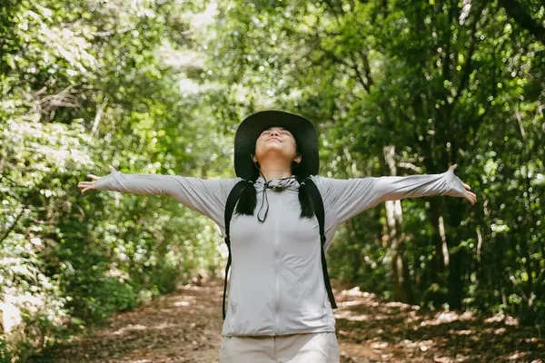Sırt çantalı genç bir gezgin ulusal parkta ya da ormanda yürüyor. Doğada eğlence sporu. Kadın çantası, ormanda yürüyüş için el sallıyor. Ormanda macera. Sırt çantasıyla yürüyüş