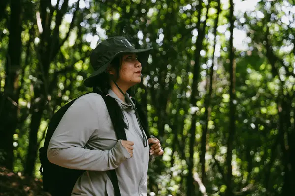 Sırt çantalı genç bir gezgin ulusal parkta ya da ormanda yürüyor. Doğada eğlence sporu. Kadın çantası, ormanda yürüyüş için el sallıyor. Ormanda macera. Sırt çantasıyla yürüyüş
