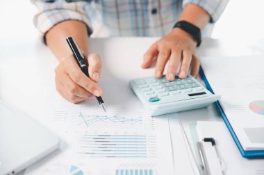 Ofisteki finans raporunu hesaplamak için hesap makinesi kullanan bir muhasebeci. işletme finansmanı, mali belgeleri düzenleyerek vergi hesaplama, gelir yatırımlarını takip etme, elle hesaplama.