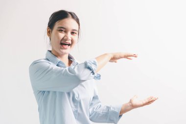 Asyalı bir kadın seviniyor, mutlu görünüyor, şampiyon, yumruk sallıyor, beyaz arka planda duruyor. Genç bir kadının yüzünde mutlu, pozitif bir ifade vardı. Parlak bir gülümsemeyle vurgulanmıştı..