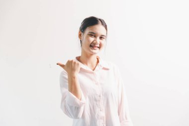 Asyalı bir kadın seviniyor, mutlu görünüyor, şampiyon, yumruk sallıyor, beyaz arka planda duruyor. Genç bir kadının yüzünde mutlu, pozitif bir ifade vardı. Parlak bir gülümsemeyle vurgulanmıştı..