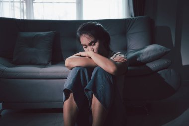 Depresyondaki kadın kanepeye oturur. Kederli insan yalnız başına oturur ve dizlerine sarılır sıkıcı üzgün üzgün sinirli sinirli. Boğucu bir yük altında umut bulmak için mücadele ediyorlar. ruh sağlığı kavramı.