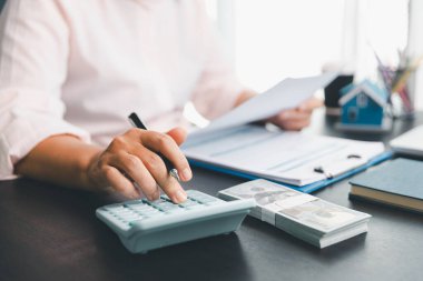 Yeniden finansman planı için konut kredisi harcamalarını kısmak ve kontrol etmek için hesap makinesi, insanların yaşam tarzı konsepti. Ev ajanları müşteri için her ay kredi sürelerini hesaplamak için hesap makinesi kullanıyorlar.