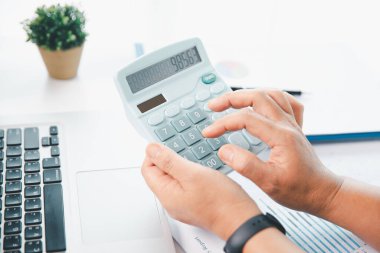 Ofisteki finans raporunu hesaplamak için hesap makinesi kullanan bir muhasebeci. işletme finansmanı, mali belgeleri düzenleyerek vergi hesaplama, gelir yatırımlarını takip etme, elle hesaplama.