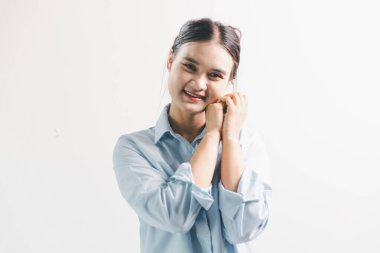 Asyalı bir kadın seviniyor, mutlu görünüyor, şampiyon, yumruk sallıyor, beyaz arka planda duruyor. Genç bir kadının yüzünde mutlu, pozitif bir ifade vardı. Parlak bir gülümsemeyle vurgulanmıştı..