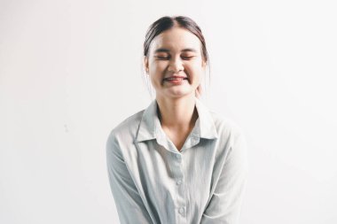 Asyalı bir kadın seviniyor, mutlu görünüyor, şampiyon, yumruk sallıyor, beyaz arka planda duruyor. Genç bir kadının yüzünde mutlu, pozitif bir ifade vardı. Parlak bir gülümsemeyle vurgulanmıştı..