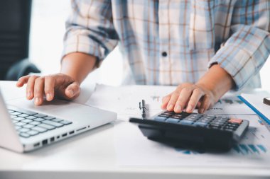 Ofisteki finans raporunu hesaplamak için hesap makinesi kullanan bir muhasebeci. işletme finansmanı, mali belgeleri düzenleyerek vergi hesaplama, gelir yatırımlarını takip etme, elle hesaplama.