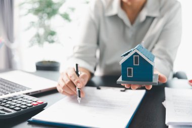 Emlakçı, müşteri temsilciliğine ev almayı kabul etti. Ev modeli, emlakçı, ev, sigorta, kredi emlak geçmişi için kontrat imzalamak isteyen müşteri. Kavram anlaşması.