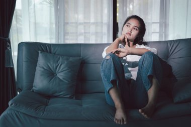 Depresyondaki kadın kanepeye oturur. Kederli insan yalnız başına oturur ve dizlerine sarılır sıkıcı üzgün üzgün sinirli sinirli. Boğucu bir yük altında umut bulmak için mücadele ediyorlar. ruh sağlığı kavramı.