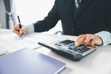 Ofisteki finans raporunu hesaplamak için hesap makinesi kullanan bir muhasebeci. işletme finansmanı, mali belgeleri düzenleyerek vergi hesaplama, gelir yatırımlarını takip etme, elle hesaplama.