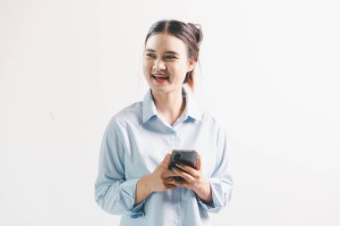 Asyalı bir kadın seviniyor, mutlu görünüyor, şampiyon, yumruk sallıyor, beyaz arka planda duruyor. Genç bir kadının yüzünde mutlu, pozitif bir ifade vardı. Parlak bir gülümsemeyle vurgulanmıştı..