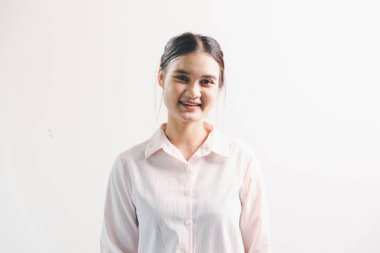 Asyalı bir kadın seviniyor, mutlu görünüyor, şampiyon, yumruk sallıyor, beyaz arka planda duruyor. Genç bir kadının yüzünde mutlu, pozitif bir ifade vardı. Parlak bir gülümsemeyle vurgulanmıştı..