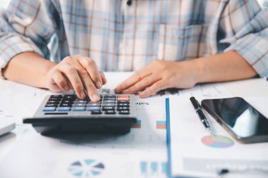 Ofisteki finans raporunu hesaplamak için hesap makinesi kullanan bir muhasebeci. işletme finansmanı, mali belgeleri düzenleyerek vergi hesaplama, gelir yatırımlarını takip etme, elle hesaplama.