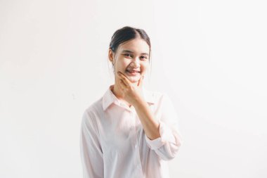 Asyalı bir kadın seviniyor, mutlu görünüyor, şampiyon, yumruk sallıyor, beyaz arka planda duruyor. Genç bir kadının yüzünde mutlu, pozitif bir ifade vardı. Parlak bir gülümsemeyle vurgulanmıştı..