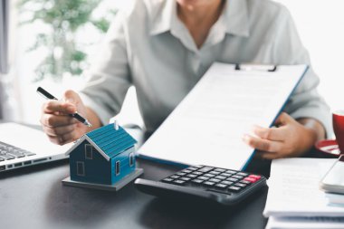 Emlakçı, müşteri temsilciliğine ev almayı kabul etti. Ev modeli, emlakçı, ev, sigorta, kredi emlak geçmişi için kontrat imzalamak isteyen müşteri. Kavram anlaşması.