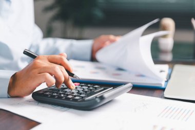 Ofis işkadını eli hesap makinesini çalıştırıyor. Finansal verileri analiz ediyor, masaları sayıyor. muhasebe, iş bütçesi planlaması için mali analiz, hesaplama desteği, finans yönetimi.