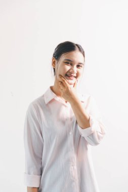 Asyalı bir kadın seviniyor, mutlu görünüyor, şampiyon, yumruk sallıyor, beyaz arka planda duruyor. Genç bir kadının yüzünde mutlu, pozitif bir ifade vardı. Parlak bir gülümsemeyle vurgulanmıştı..