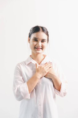 Asyalı bir kadın seviniyor, mutlu görünüyor, şampiyon, yumruk sallıyor, beyaz arka planda duruyor. Genç bir kadının yüzünde mutlu, pozitif bir ifade vardı. Parlak bir gülümsemeyle vurgulanmıştı..