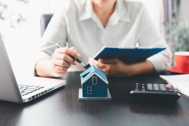 Emlakçı, müşteri temsilciliğine ev almayı kabul etti. Ev modeli, emlakçı, ev, sigorta, kredi emlak geçmişi için kontrat imzalamak isteyen müşteri. Kavram anlaşması.