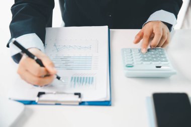 Ofisteki finans raporunu hesaplamak için hesap makinesi kullanan bir muhasebeci. işletme finansmanı, mali belgeleri düzenleyerek vergi hesaplama, gelir yatırımlarını takip etme, elle hesaplama.