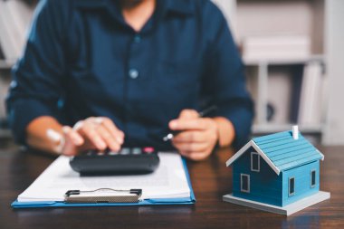 Kadın eli küçük minyatür bir oyuncak evi tutuyor, kendi emlak konseptine taşınma hayalini sembolize eden kadın emlak yatırımını, ipotek planlama, güvenli bir gelecek sigortasını temsil ediyor..