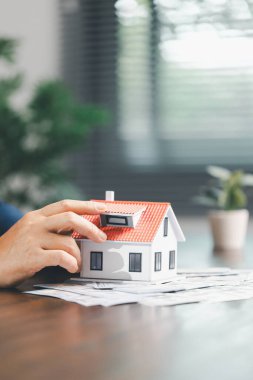 Para sikkelerinin yanına yerleştirilen ev modeli ev satın alma, yatırım, ipotek seçenekleri, konut kredileri, yeniden finanse etme, akıllı finans stratejileri için tasarruf ve mali planlama kavramını gözler önüne seriyor