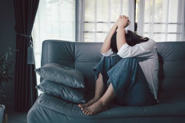 Depresyondaki kadın kanepeye oturur. Kederli insan yalnız başına oturur ve dizlerine sarılır sıkıcı üzgün üzgün sinirli sinirli. Boğucu bir yük altında umut bulmak için mücadele ediyorlar. ruh sağlığı kavramı.