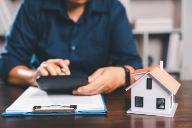 Kadın eli küçük minyatür bir oyuncak evi tutuyor, kendi emlak konseptine taşınma hayalini sembolize eden kadın emlak yatırımını, ipotek planlama, güvenli bir gelecek sigortasını temsil ediyor..