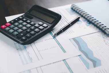 Denetçi, iş dünyası için ayrıntılı bir mali rapor hazırlamada muhasebe, denetim ve finans kavramını temsil eden bir hesap makinesi kullanarak mali beyanat ve bilançoyu masasında gözden geçirir..