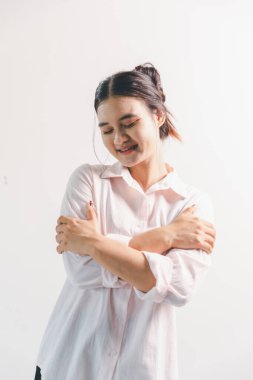 Asyalı bir kadın seviniyor, mutlu görünüyor, şampiyon, yumruk sallıyor, beyaz arka planda duruyor. Genç bir kadının yüzünde mutlu, pozitif bir ifade vardı. Parlak bir gülümsemeyle vurgulanmıştı..