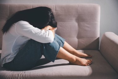 Depresyondaki kadın kanepeye oturur. Kederli insan yalnız başına oturur ve dizlerine sarılır sıkıcı üzgün üzgün sinirli sinirli. Boğucu bir yük altında umut bulmak için mücadele ediyorlar. ruh sağlığı kavramı.