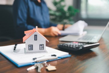 Kadın eli küçük minyatür bir oyuncak evi tutuyor, kendi emlak konseptine taşınma hayalini sembolize eden kadın emlak yatırımını, ipotek planlama, güvenli bir gelecek sigortasını temsil ediyor..