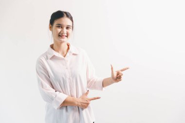 Asyalı bir kadın seviniyor, mutlu görünüyor, şampiyon, yumruk sallıyor, beyaz arka planda duruyor. Genç bir kadının yüzünde mutlu, pozitif bir ifade vardı. Parlak bir gülümsemeyle vurgulanmıştı..