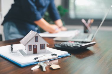 Kadın eli küçük minyatür bir oyuncak evi tutuyor, kendi emlak konseptine taşınma hayalini sembolize eden kadın emlak yatırımını, ipotek planlama, güvenli bir gelecek sigortasını temsil ediyor..