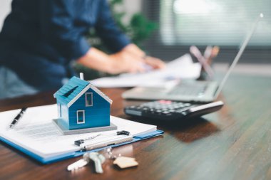 Kadın eli küçük minyatür bir oyuncak evi tutuyor, kendi emlak konseptine taşınma hayalini sembolize eden kadın emlak yatırımını, ipotek planlama, güvenli bir gelecek sigortasını temsil ediyor..