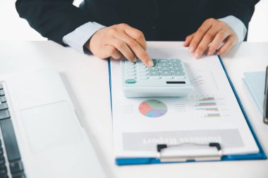 Ofisteki finans raporunu hesaplamak için hesap makinesi kullanan bir muhasebeci. işletme finansmanı, mali belgeleri düzenleyerek vergi hesaplama, gelir yatırımlarını takip etme, elle hesaplama.