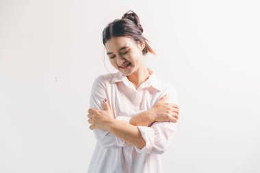 Asyalı bir kadın seviniyor, mutlu görünüyor, şampiyon, yumruk sallıyor, beyaz arka planda duruyor. Genç bir kadının yüzünde mutlu, pozitif bir ifade vardı. Parlak bir gülümsemeyle vurgulanmıştı..