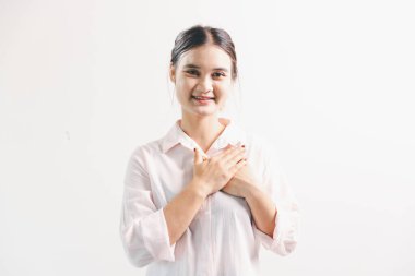 Asyalı bir kadın seviniyor, mutlu görünüyor, şampiyon, yumruk sallıyor, beyaz arka planda duruyor. Genç bir kadının yüzünde mutlu, pozitif bir ifade vardı. Parlak bir gülümsemeyle vurgulanmıştı..