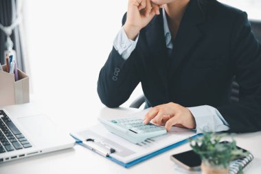 Ofisteki finans raporunu hesaplamak için hesap makinesi kullanan bir muhasebeci. işletme finansmanı, mali belgeleri düzenleyerek vergi hesaplama, gelir yatırımlarını takip etme, elle hesaplama.