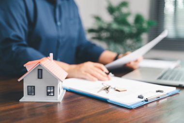 Kadın eli küçük minyatür bir oyuncak evi tutuyor, kendi emlak konseptine taşınma hayalini sembolize eden kadın emlak yatırımını, ipotek planlama, güvenli bir gelecek sigortasını temsil ediyor..