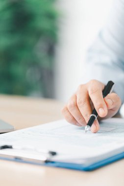 İş planlama ve finansal analiz kavramı. Bir iş kadını, modern ofis masasındaki bütçe yönetimi için dizüstü bilgisayar ve hesap makinesi kullanarak dosya ve raporlarla ilgili notlar yazar..