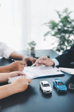 İş adamı araba kredisini hesap makinesiyle açıklıyor, müşteri ofis masasında oyuncak araba ve belgelerle otomobil finansmanı anlaşmasını tartışıyor, araç kredisi, sigorta veya araba kiralama kavramını anlatıyor. araba kredisi.