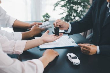 Müşteri, sözleşme imzaladıktan sonra satıcıdan araba anahtarı, ofis masasında başarılı bir otomobil satın alma ve finans anlaşması, araç kredisi, kiralama, sigorta veya mülkiyet konsepti alıyor. araç kredisi.