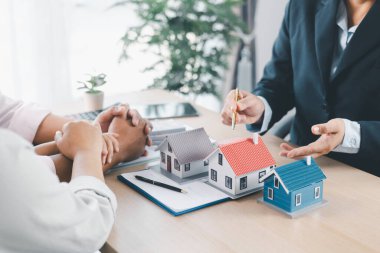 Ev modeli, arka planda sözleşme, emlak yatırımı konsepti, ipotek kredisi, ev sahipliği, gayrimenkul ticareti ve mali anlaşma konularını tartışan bulanık insanlarla birlikte masada..