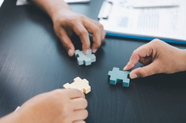 Ahşap yapboz parçalarını bir arada tutan insanlarla iş birliği, strateji, problem çözme, ortaklık ve modern ofiste kurumsal başarının sembolü. iş ekibi çalışması.